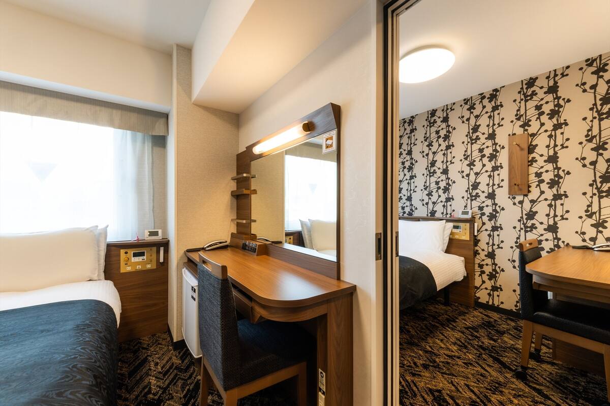 Ein Hotelzimmer mit Bett, Schreibtisch mit Spiegel, Nachttisch, Stuhl und Teppichboden.