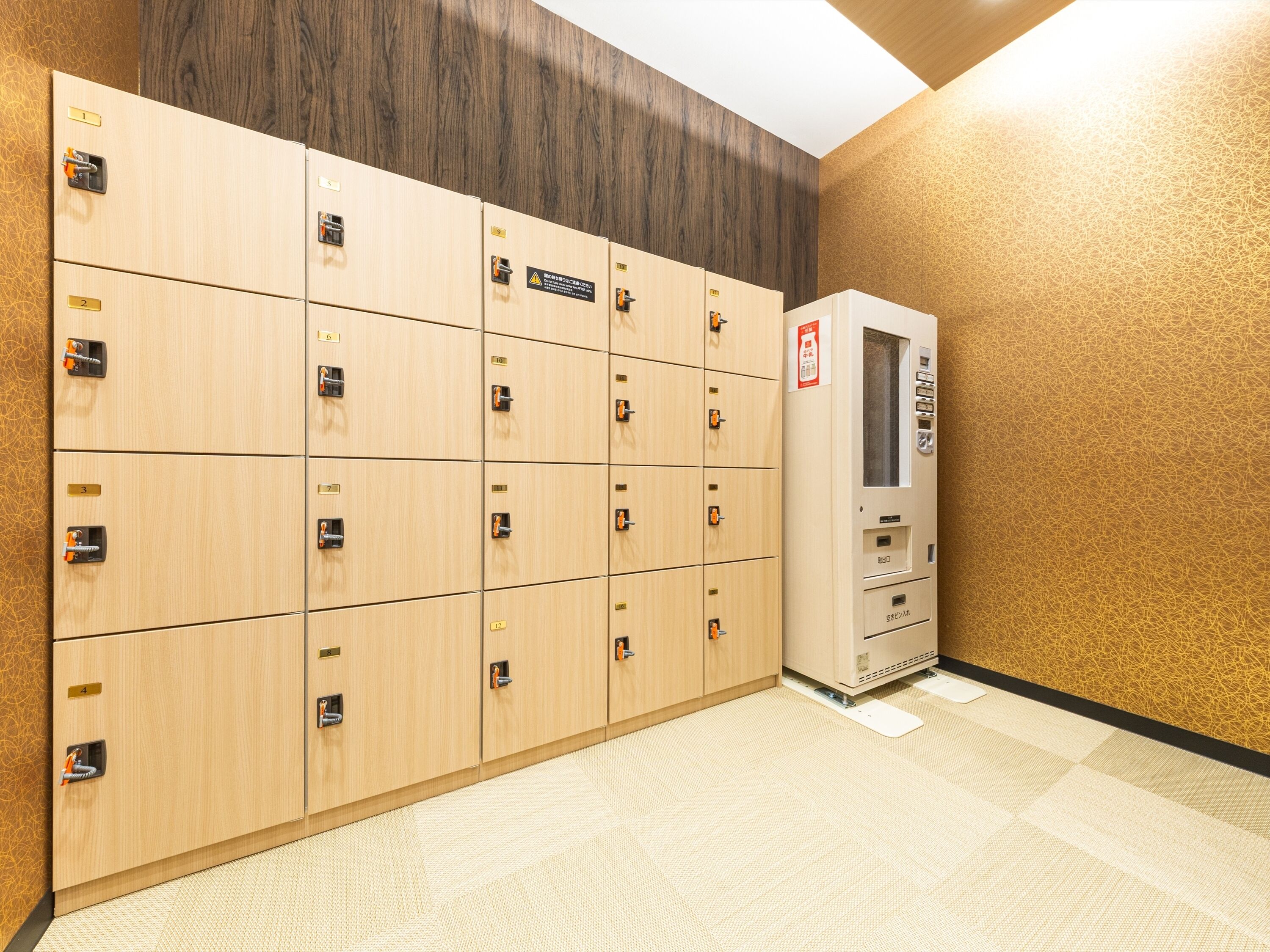 A row of wooden lockers with numbered labels, a vending machine, and a patterned floor.