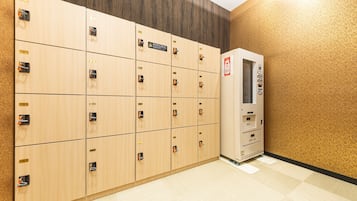 A row of wooden lockers with numbered labels, a vending machine, and a patterned floor.