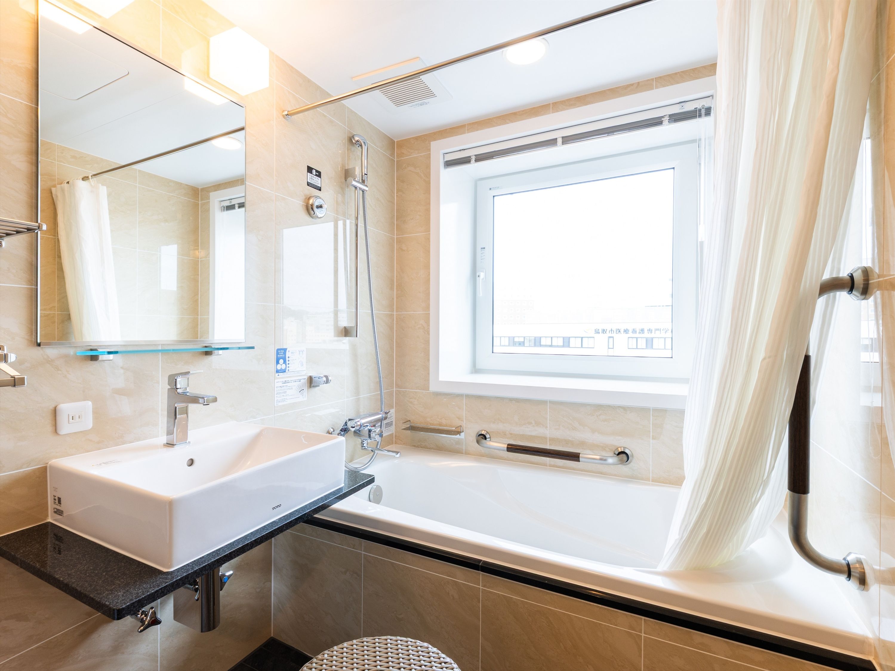 A modern bathroom with a large bathtub, a separate shower area, a vanity with a sink, and a large mirror.