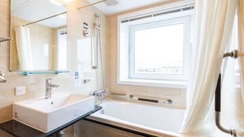 A modern bathroom with a large bathtub, a separate shower area, a vanity with a sink, and a large mirror.