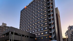 Un edificio de gran altura con un cartel que dice "APA HOTEL" en la parte superior.