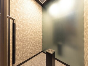Un coin de pièce avec des murs à motifs, une porte et une petite poubelle.