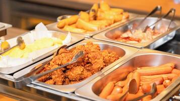 Un bufé con diversos alimentos, como pollo frito, papas fritas y otros platos.