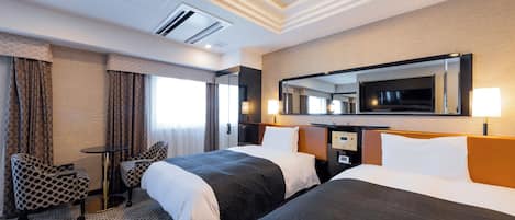 A hotel room with two beds, a desk, a chair, a large mirror, and a ceiling light.