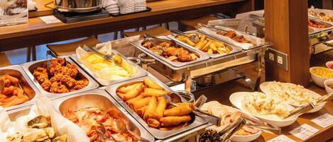 En buffet med et bredt udvalg af retter, herunder friturestegte varme retter, grøntsager og desserter.