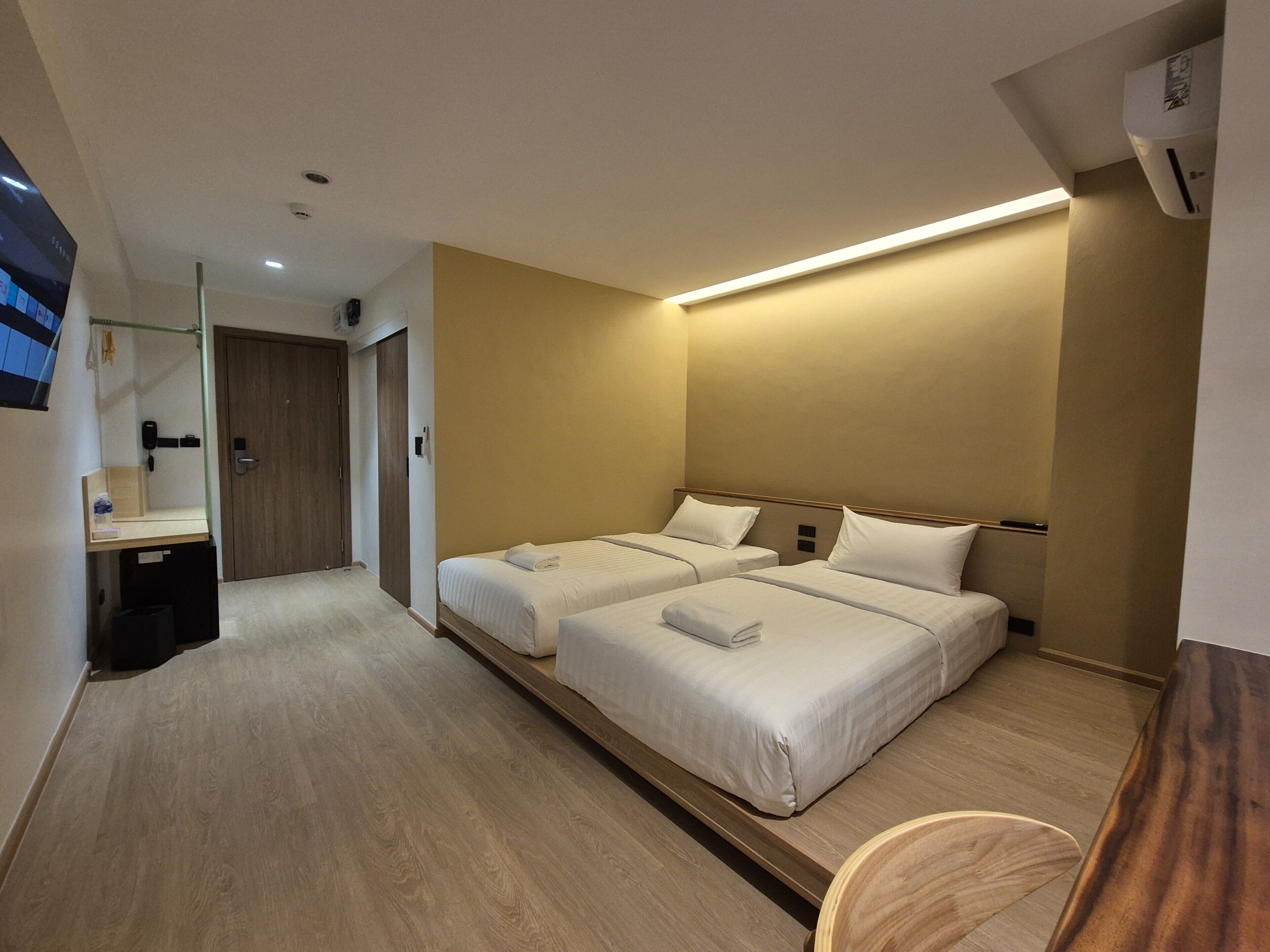 Une chambre d’hôtel avec deux lits, un plancher en bois, un bureau et un miroir.