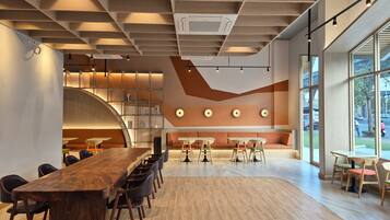 A modern interior with a long wooden table and chairs, a curved seating area, and large windows offering a view of the outside.
