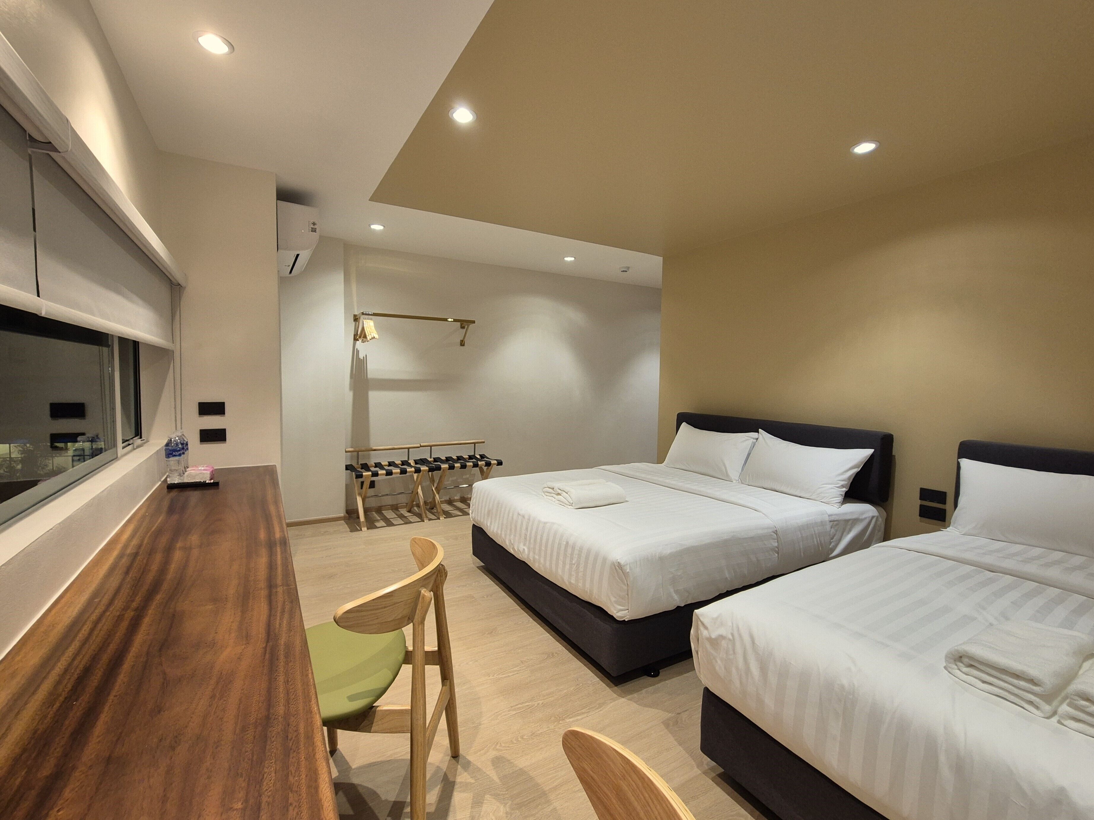 Habitación de hotel con dos camas, un escritorio, una silla y una ventana.