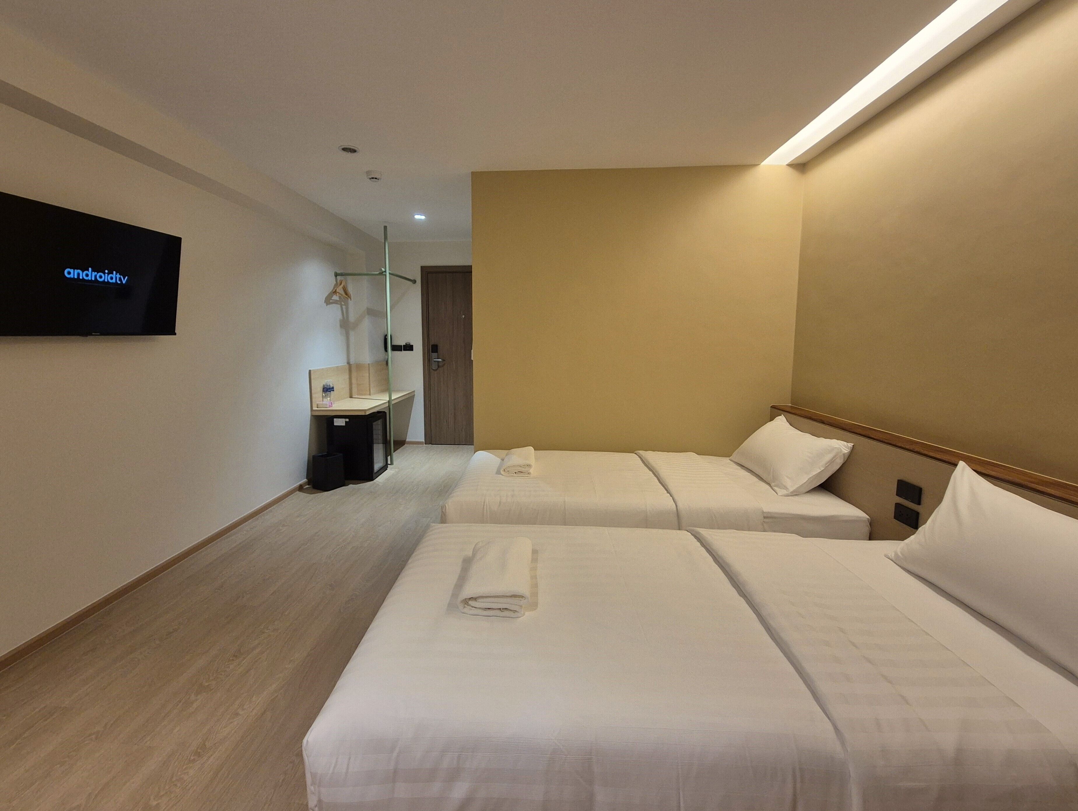 Une chambre d’hôtel avec deux lits, un téléviseur fixé au mur, un bureau et un miroir.