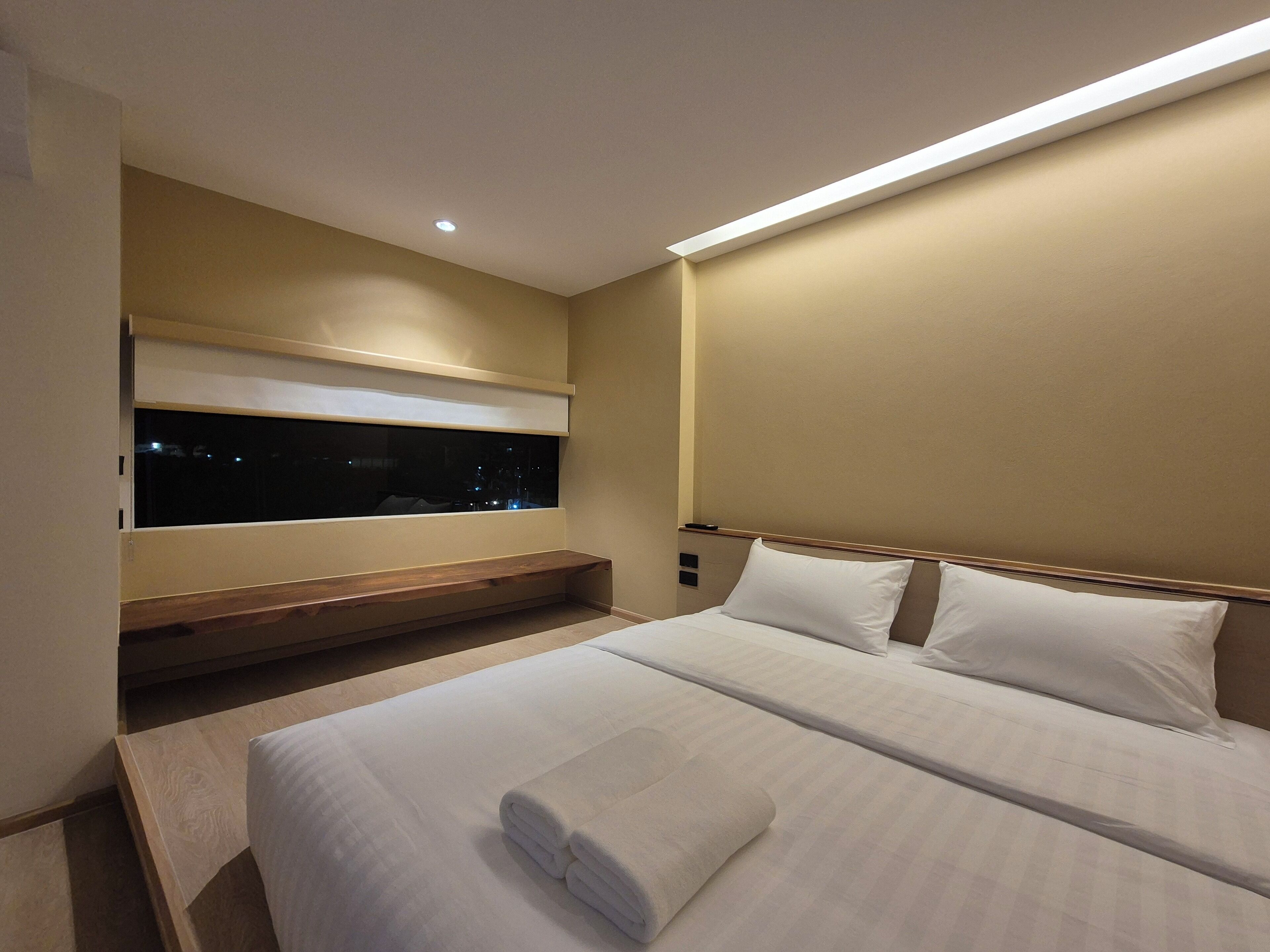 Una habitación de hotel con una cama grande, un ventanal con vista al cielo nocturno y un banco integrado debajo de la ventana.