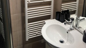 Une salle de bain avec un lavabo blanc, un miroir et un porte-serviettes.