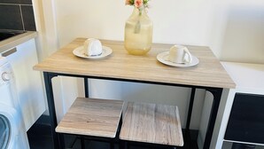 Une petite cuisine avec une table en bois, deux tasses blanches et un vase rempli de fleurs.