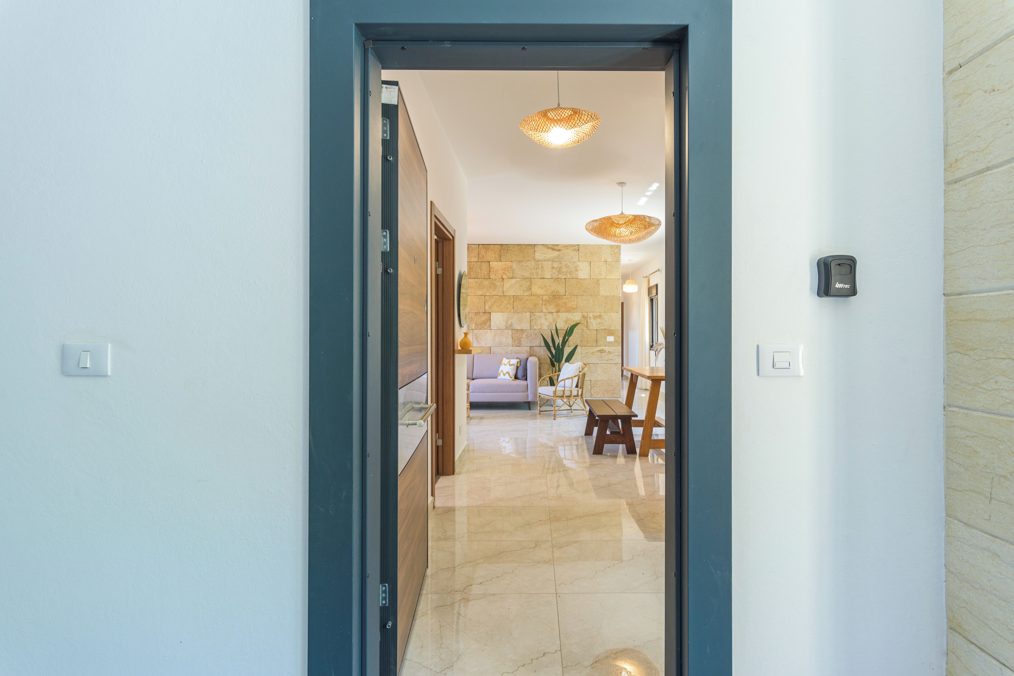 A hallway leading to a living area with a stone wall, a sofa, and a dining table.