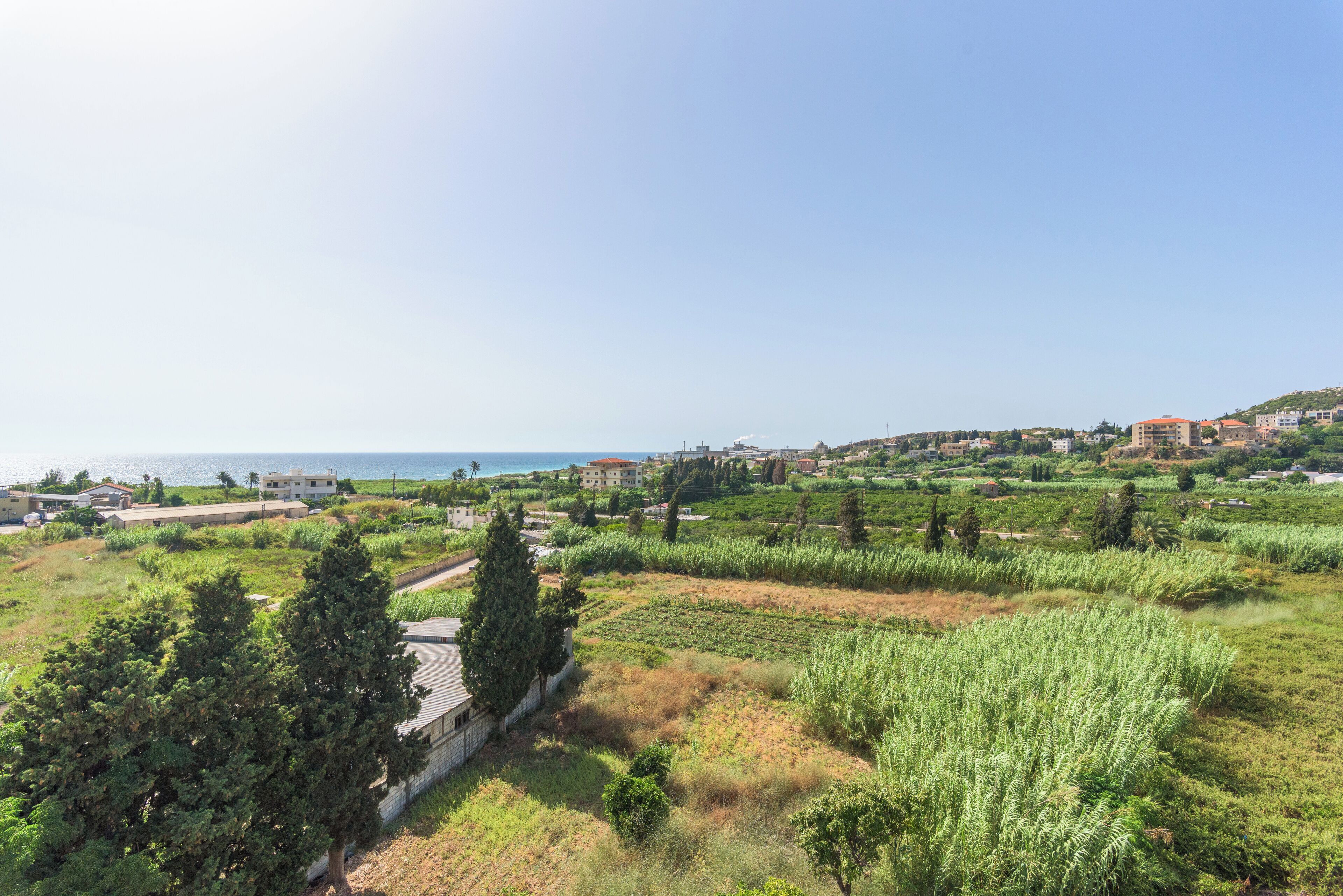 A coastal landscape with buildings, greenery, and a clear sky.