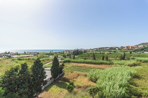 A coastal landscape with buildings, greenery, and a clear sky. - Glow Studios & Apartments in Batroun  (Batroun)