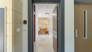 A hallway with a marble floor, a wooden bench, and a stone wall in the background.