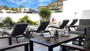 A rooftop terrace with lounge chairs and tables, overlooking a mountainous landscape. - Casa M Cabo, Modern Luxury Villa, Private Pool & Hot Tub (Cabo San Lucas)