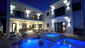 A modern two-story house with a swimming pool, outdoor seating, and a well-lit interior. - Casa M Cabo, Modern Luxury Villa, Private Pool & Hot Tub (Cabo San Lucas)