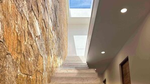 A staircase with a stone wall on one side and a skylight above. - Casa M Cabo, Modern Luxury Villa, Private Pool & Hot Tub (Cabo San Lucas)