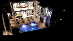 Un moderno edificio residenziale a più livelli con una terrazza sul tetto, una piscina e un'area pranzo.