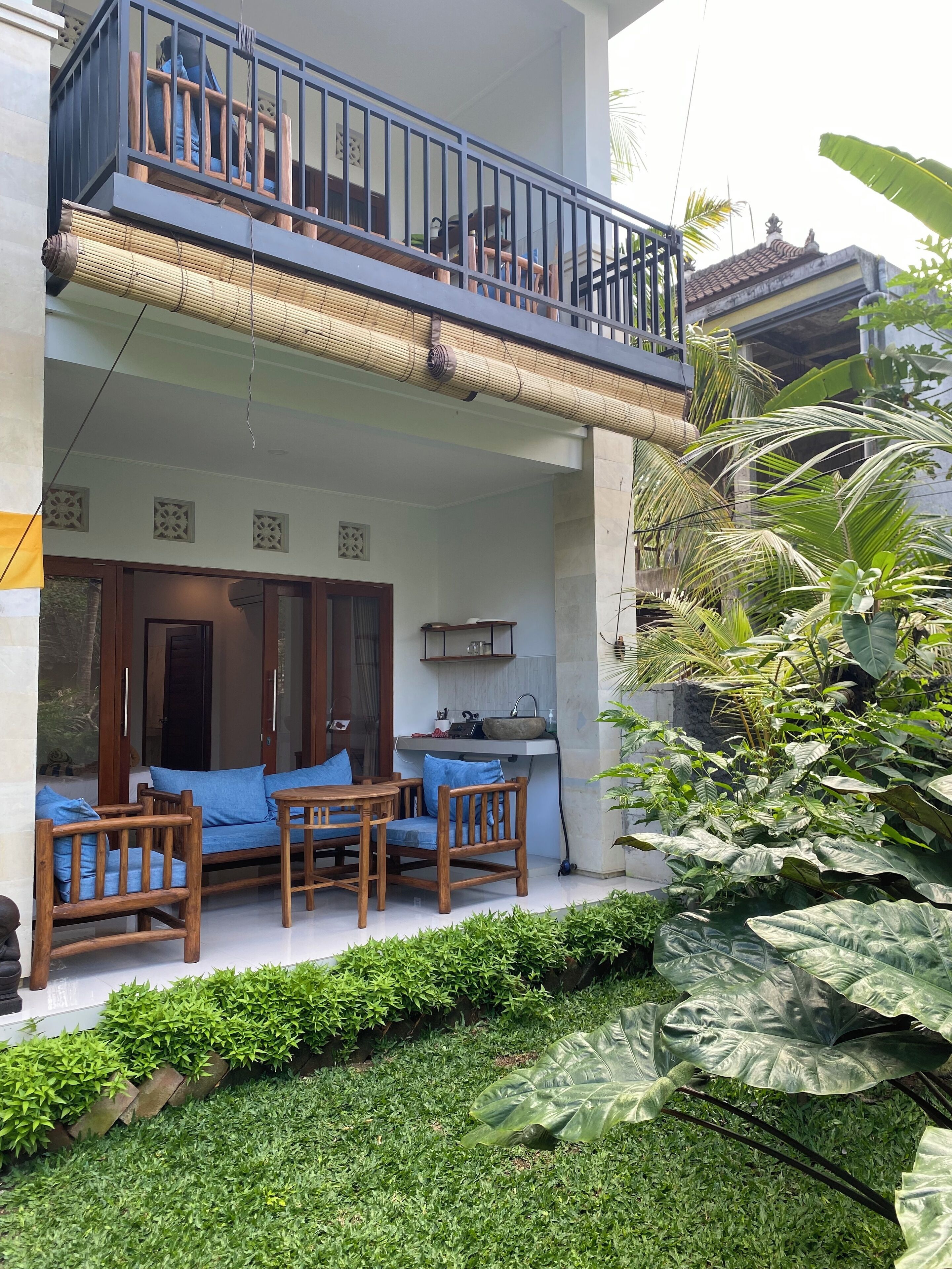 A two-story building with a balcony, a kitchen area, and a seating area with wooden furniture.