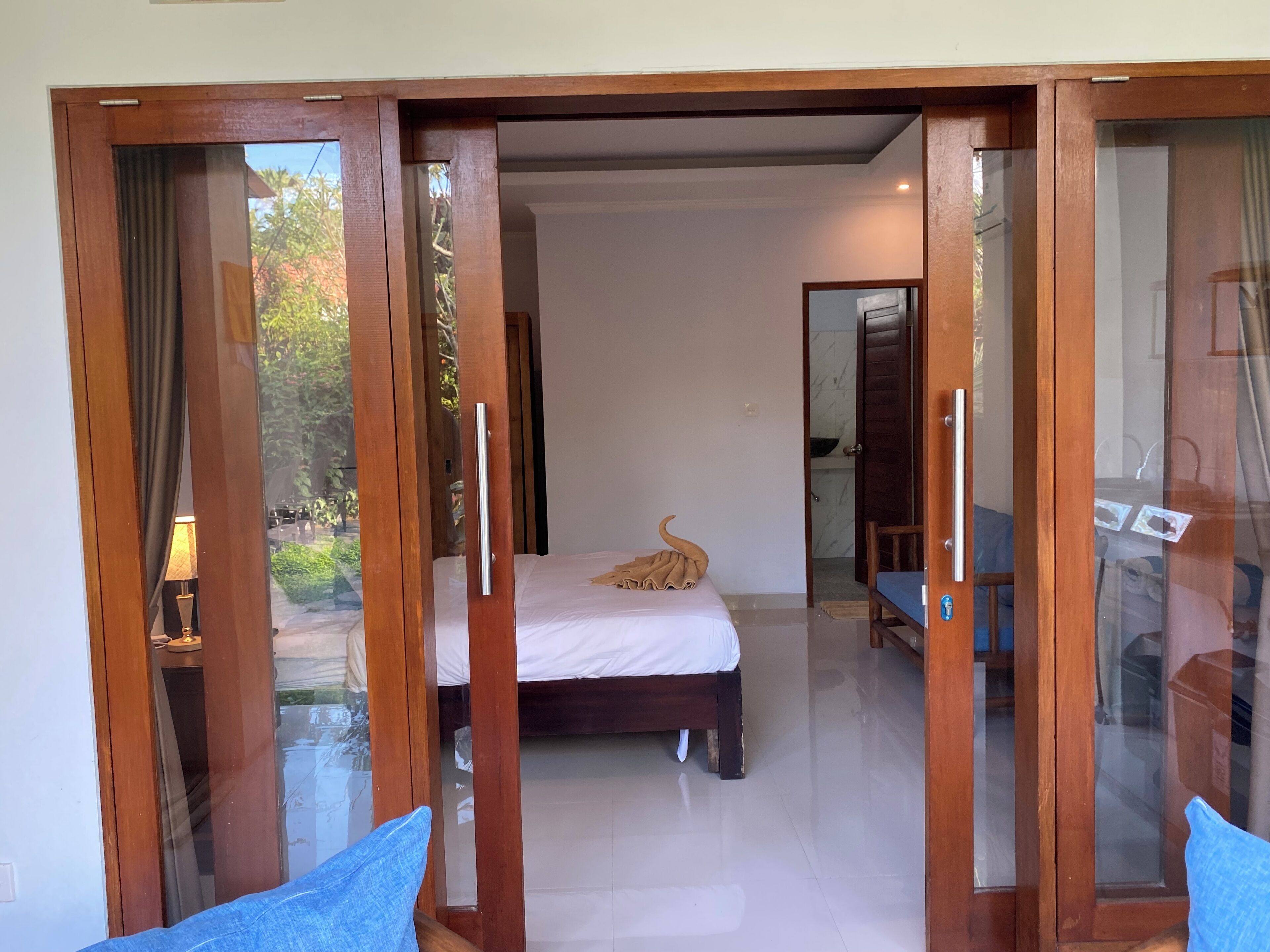 A bedroom with a bed, a wooden door, and a view of the outdoors.
