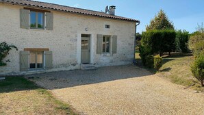A stone house with a gravel driveway and a small garden.