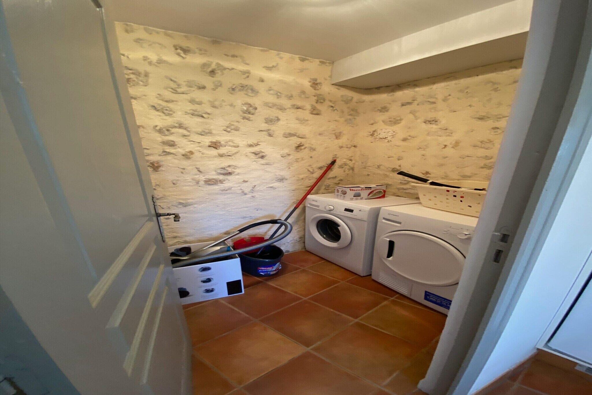 A laundry room with a washing machine, dryer, and a mop.