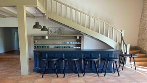 Une cuisine avec un coin bar, un escalier et un sol carrelé.