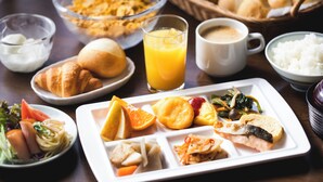 Ein Frühstückstisch mit Croissants, Müsli, Obst und verschiedenen Speisen.