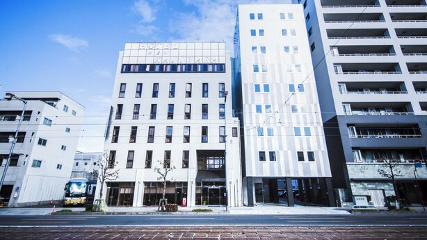 Ein modernes Hotel mit schlichter Fassade, zahlreichen Fenstern und blauem Himmel.