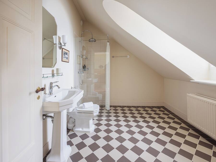 Un baño con piso a cuadros, un lavamanos blanco, un inodoro y una ducha.