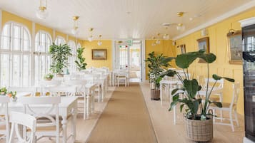 Ein Restaurant mit weißer Möbel, gelben Wänden und hängenden Kristalllüstern.