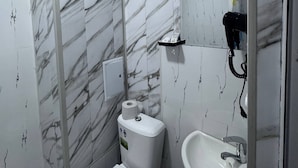 Ein Badezimmer mit Marmorwänden, einer Toilette, einem Waschbecken und einem Spiegel.