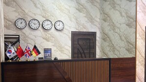 Ein Empfangsschalter mit Marmorwand, Uhren, Flaggen und einer Holzvertäfelung.