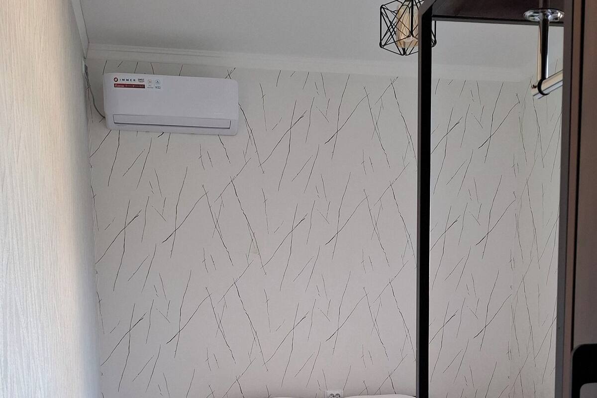 A bedroom with a bed, bedside tables, a hanging light fixture, and a patterned rug.