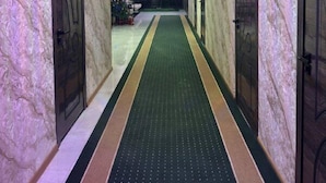 Ein Korridor mit Marmorwänden, einem grünen Teppich und Türen mit geometrischem Muster.