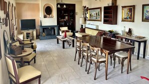 A spacious living room with a fireplace, a television, and a dining area with a large wooden table and chairs. - Sea view villa apartment Monastiraki Nafpaktos (Monastiraki)