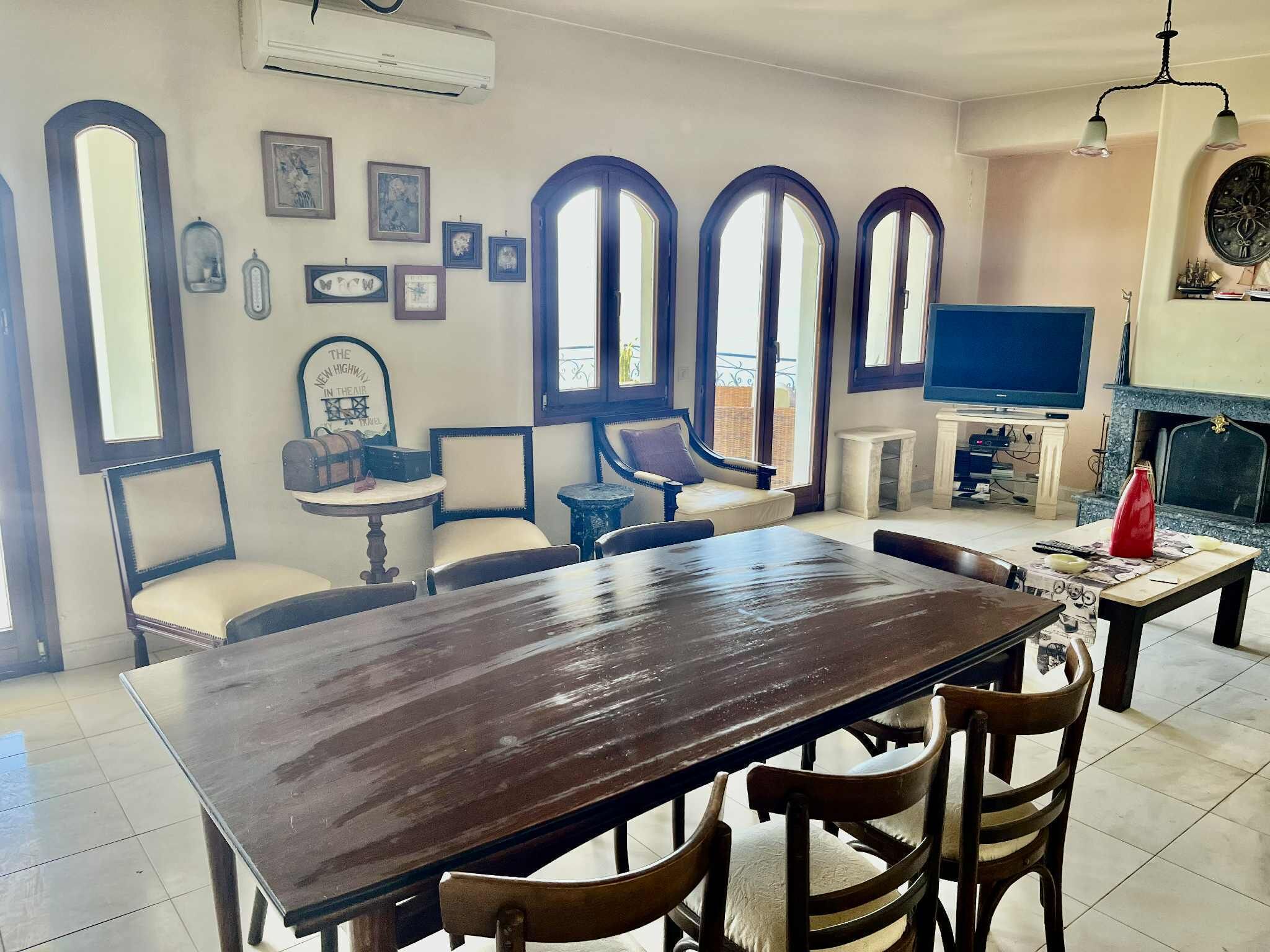 A dining area with a large wooden table, chairs, and a television.