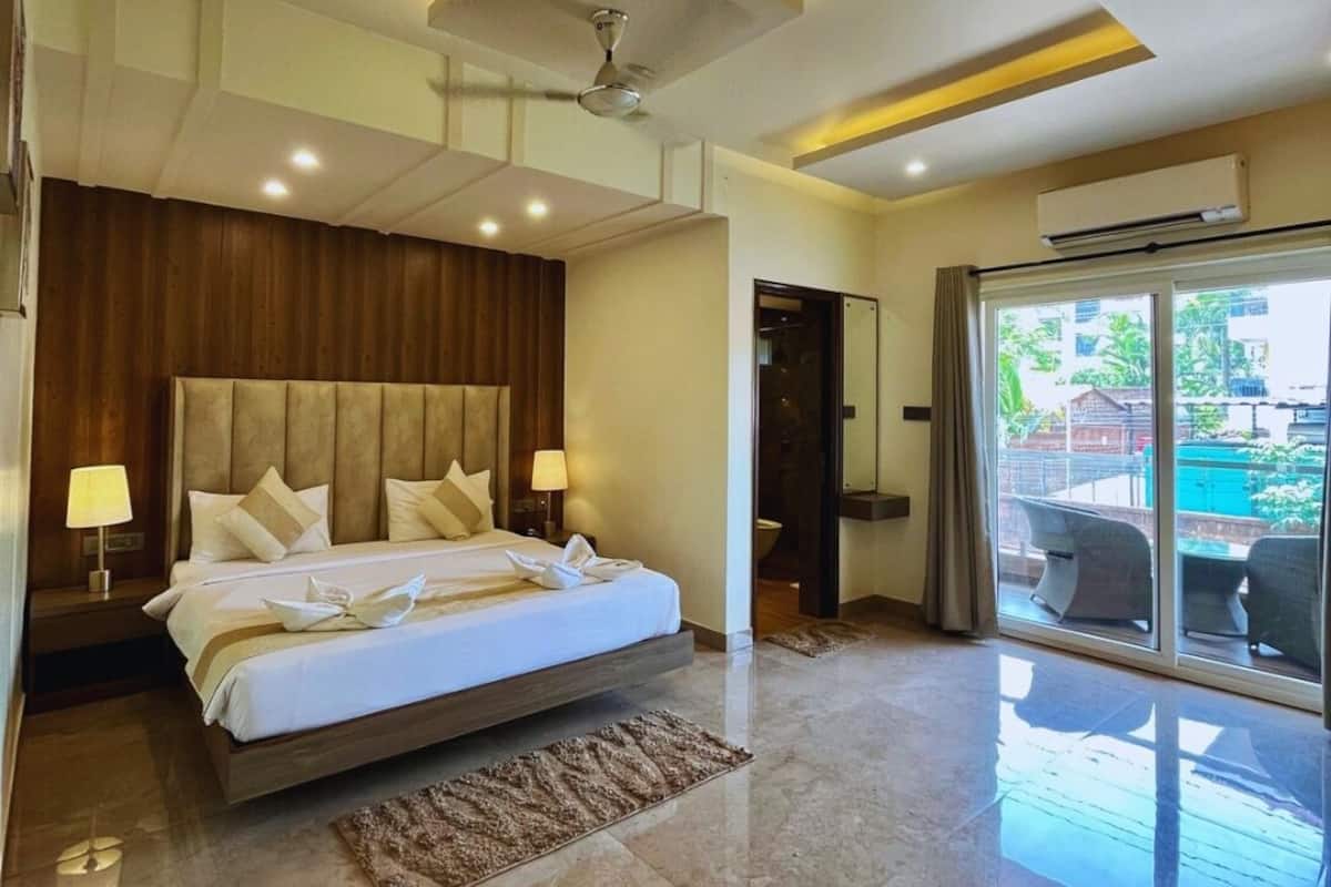 A modern bedroom with a large bed, a ceiling fan, and a view of the outside through a sliding glass door.