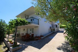 A two-story building with a balcony, outdoor seating, and a garden area.
