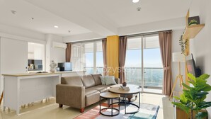 Un salon moderne avec un canapé, une table basse et une vue sur la ville grâce à de grandes fenêtres.