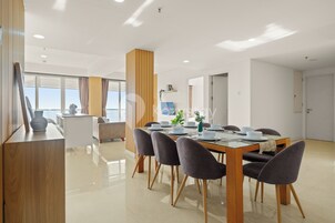 Un comedor moderno con una mesa de madera, sillas grises tapizadas y una encimera blanca con un florero.