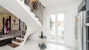 Una cocina moderna con un refrigerador empotrado, un horno de acero inoxidable y una puerta de vidrio que da a un balcón.