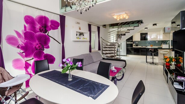 Una sala de estar moderna con comedor, una escalera y una cocina.
