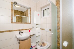 Ein Badezimmer mit Waschbecken, Spiegel und einer Duschkabine aus Glas.
