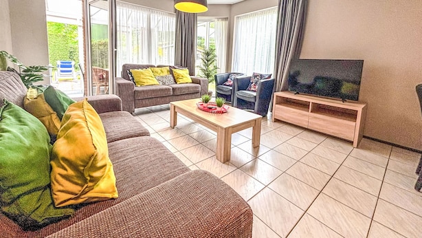 Een woonkamer met een bank, fauteuils, een salontafel en een televisie.