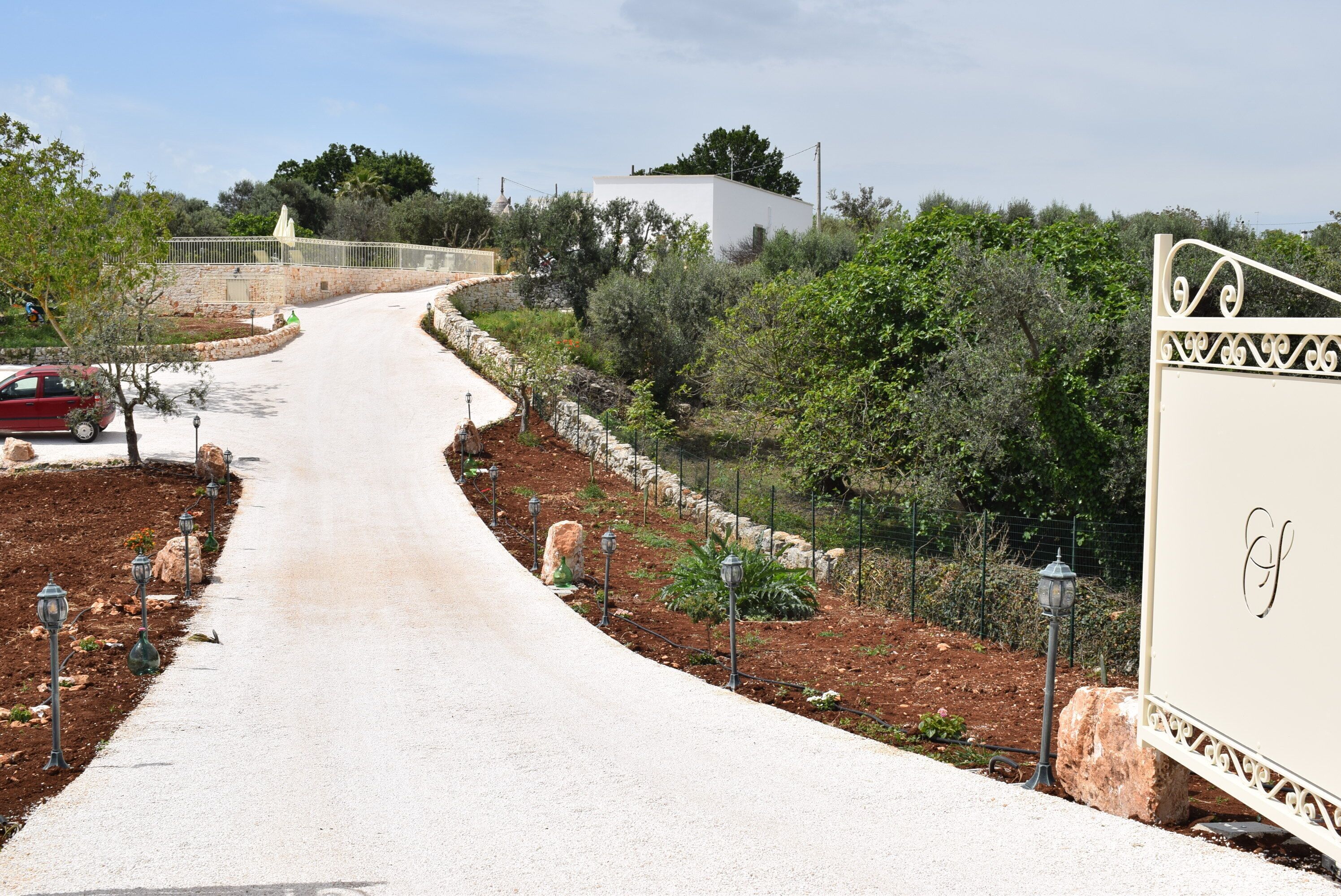 A paved pathway leading to a white building with a decorative gate.