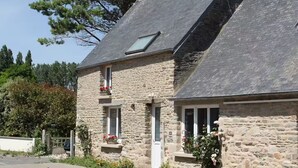 Un bâtiment en pierre avec un toit en pente, un petit balcon et des jardinières.